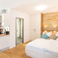 1 Zimmer-Apartment Innenansicht Bett und Blick ins Bad
